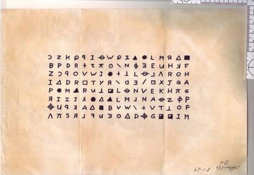 A photograph of one of the Zodiac's cipher pages on aged paper — rows of hand-drawn symbols including circles, triangles, letters, and crosshair shapes arranged in a neat grid, with a ruler laid alongside as an evidence marker.